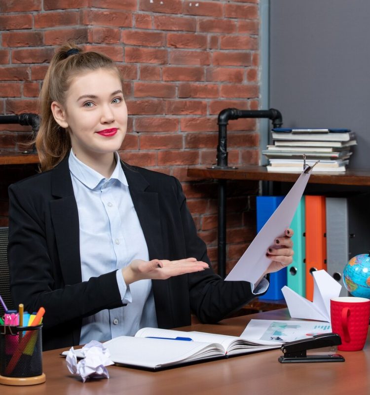 top-view-young-female-sitting-table-showing-document-office_140725-106107